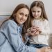A loving mother with her daughter drinking a smoothie and sharing a warm moment in the kitchen.